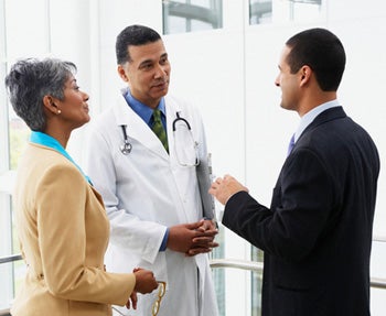 Médico hablando con hombre y mujer de negocios